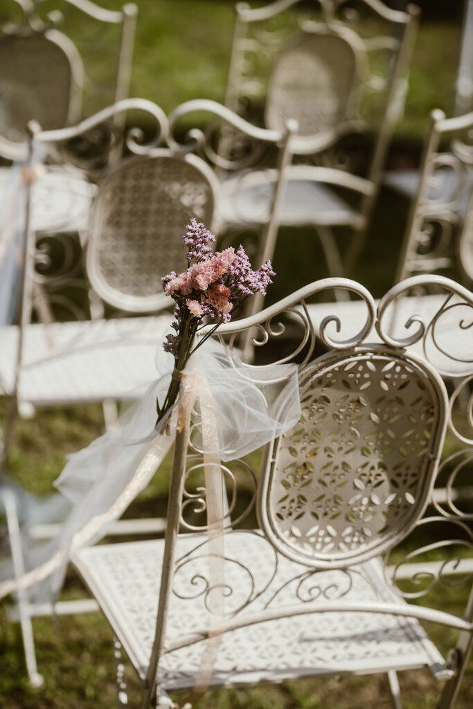 Detalle de silla blanca elegante con un pequeño ramo de flores en una ceremonia